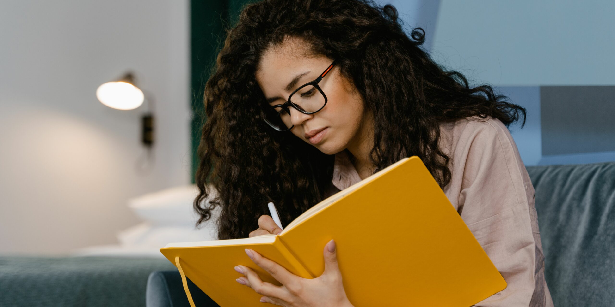 mujer-de-cabello-rizado-escribiendo-en-un-diario-de-color-amarillo