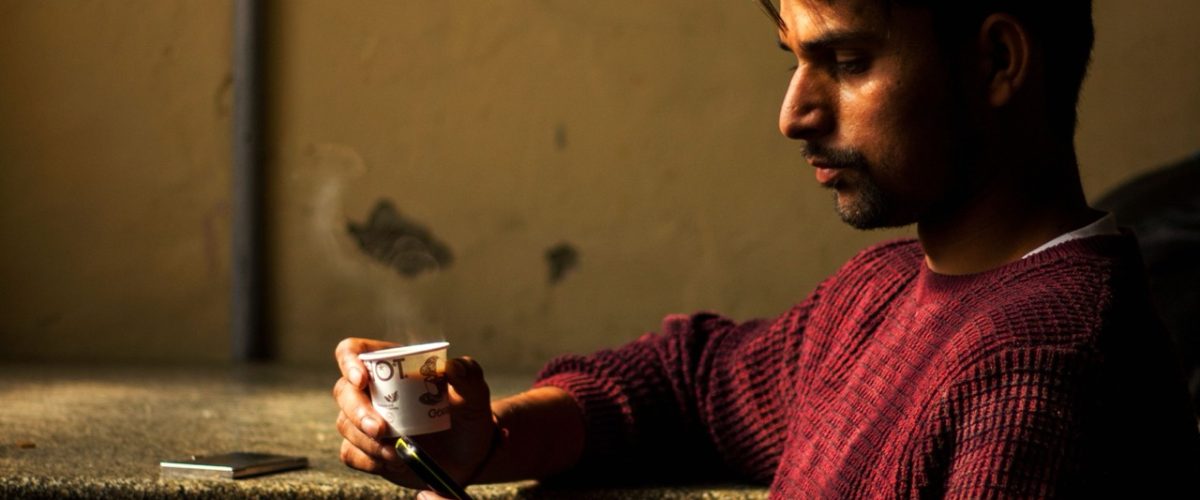 hombre-sentado-viendo-su-movil-y-tomando-cafe